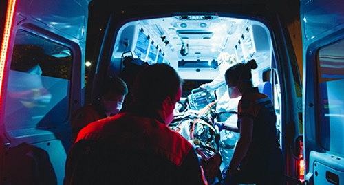 Image of a person being lifted into the back of an ambulance. 